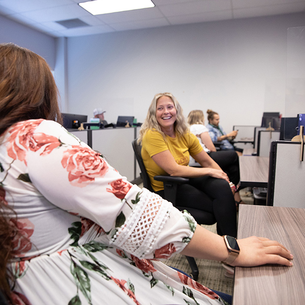 two women laughing at their desks